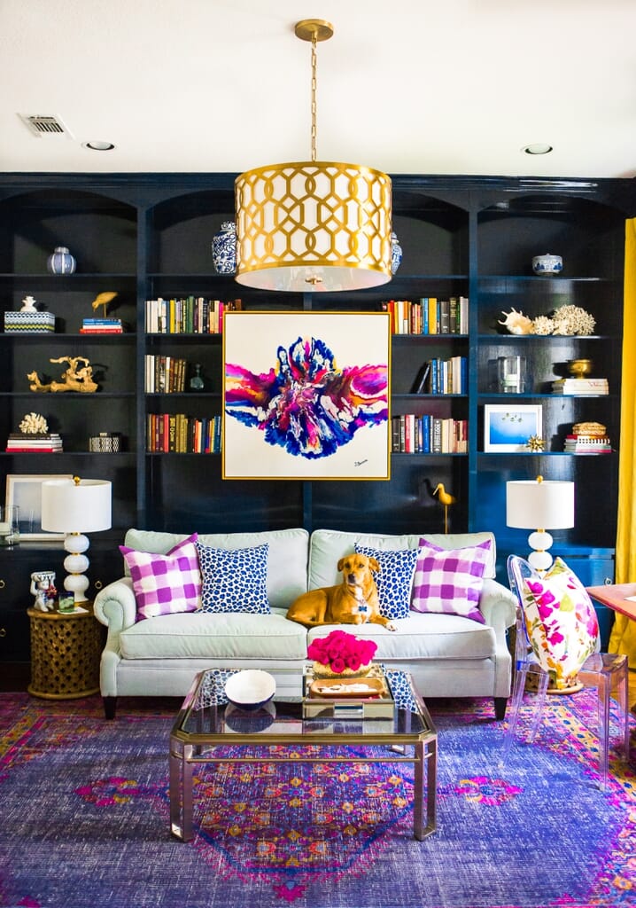 A Maximalist living room with bright, patterned art and accessories, glossy blue built-in bookcases and a patterned light fixture. Maximalism Design: How to Add Bold Style to Your Home - LightsOnline Blog