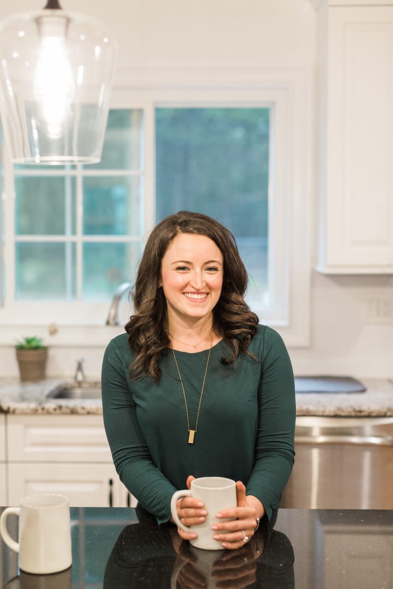 Elizabeth from The Clean Eating Couple pictured in her remodeled kitchen with Savoy House pendants